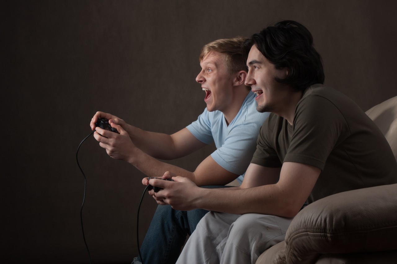 two-friends-are-focused-on-playing-video-games-on-gray-